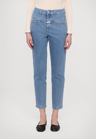 Lichtblauwe hoge taille jeans met een rechte pasvorm, voorzien van zijzakken, subtiele stikseldetails en enkel lengte. Zwarte ballerina's maken de look compleet.