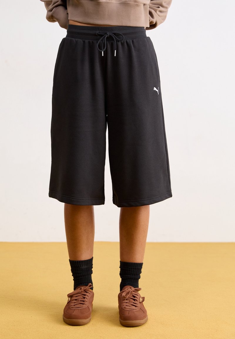 Schwarze Shorts aus weichem Material mit einem elastischen Bund und einem Kordelzug, versehen mit einem kleinen weißen Logo auf der linken Seite.