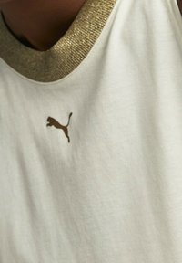 White tank top featuring a gold ribbed neckline and a small brown Puma logo on the chest. The fabric appears soft and lightweight.