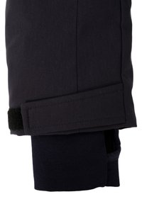 Gamba di pantaloni nera con taglio dritto, dotata di una cinghia in velcro e di un risvolto interno blu scuro, texture strutturata e linee pulite.