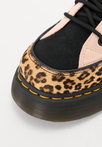 Fekete és rózsaszín sneaker leopárdmintás panelekkel, velúr textúrával, vastag fekete talppal és sárga öltés részletekkel az oldalon.