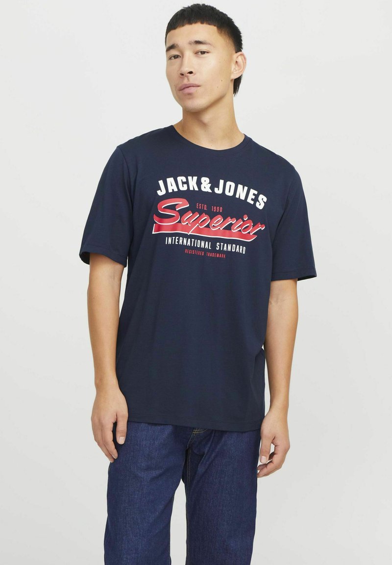 Marineblaue Baumwoll-T-Shirt mit auffälligem roten und weißen Text. Rundhalsausschnitt und kurze Ärmel. Ideal kombiniert mit Jeans für einen lässigen Look.