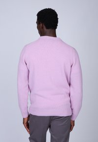 Pull en tricot rose clair avec un ourlet et des poignets côtelés ; design simple, col rond, texture lisse et manches longues.