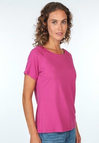 Fuchsia kurzärmliges Oberteil mit rundem Ausschnitt, aus glattem Stoff gefertigt. Die Passform ist leger und verfügt über Seitennähte für eine schöne Form.