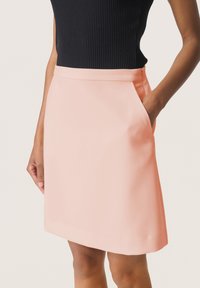 Šviesiai rožinė A formos sijonas su šoniniais kišenėmis, pagamintas iš lygios medžiagos. Turintis tvarkingą apvadą ir tvirtą juosmenį.