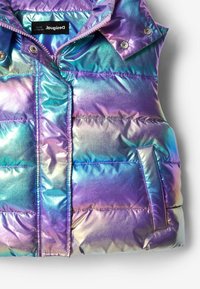 Chaleco acolchado iridiscente con cierre frontal de cremallera, botones a presión y un bolsillo externo, en una mezcla de tonos púrpura, azul y verde.