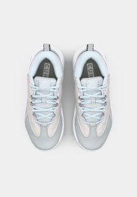 Baskets de sport gris clair avec une surface lisse, des accents en mesh et des lacets bleus. Présente un logo sur la languette et un col matelassé.