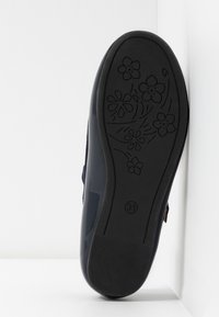 Granatowe buty wsuwane z teksturowaną cholewką, płaską podeszwą zdobioną grawerowanymi kwiatowymi wzorami oraz gładkim, błyszczącym wykończeniem obcasa.