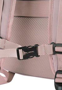 Mochila beige con un panel de malla texturizada en rosa y correas ajustables. Hebillas de plástico negro aseguran las correas para un ajuste ceñido.