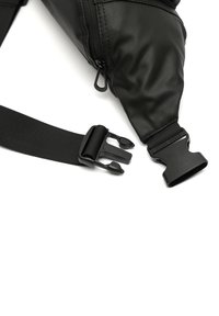 Borsa a tracolla nera in tessuto texturizzato con zip e cinturino in plastica regolabile. Presenta bordi lisci e un design minimalista.