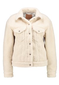 Veste en polaire couleur crème avec un extérieur texturé, deux poches poitrine, fermeture à boutons-pression et col. Présente des poignets et un ourlet côtelés.