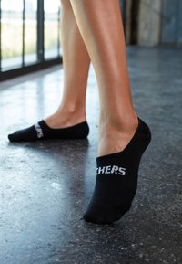 Fekete bokazokni, puha anyagból, bordázott mandzsettával, fehér felirattal a külső oldalon, ami a "STITCHERS" szöveget tartalmazza.