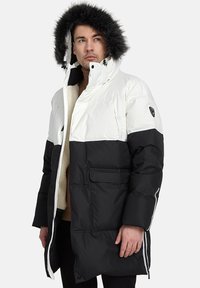 Pūkains parkas ar baltu augšdaļu un melnu apakšdaļu, ar kažokādas oderi, divām priekšējām kabatām un rāvējslēdzēja aizdari; teksturēta audums ar gludu apdari.