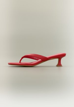 Sarkani piepirkstu sandale ar kvadrātveida purngalu, zemu izliekta papēža augstumu un polsterētām siksniņām uz vienkārša gaiša fona.