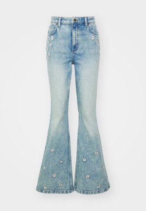 Jean évasé bleu clair à taille haute, doté de fleurs blanches brodées et d'un design classique à cinq poches. La texture en denim est visible.