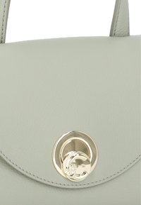 Sac à main en cuir gris clair avec un rabat incurvé, quincaillerie circulaire dorée et détails de couture soignés. Design compact, style minimaliste.