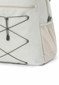 Zaino grigio chiaro con un tessuto testurizzato, dotato di un design con corda bungee, una tasca laterale e un compartimento con zip nella parte superiore.