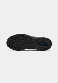 Semelle de chaussure en caoutchouc noir avec motif de bande de roulement texturé et accents bleus près du talon, présentée sur un fond clair uni.