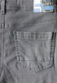 Jeans de mezclilla gris con un bolsillo trasero con un contorno cosido, una etiqueta adjunta en la cintura y una textura suave.