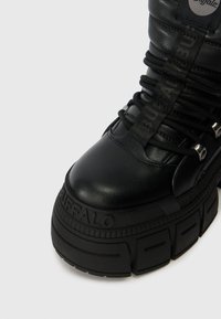 Musthave musta nahast kõrge säärega sneaker paksu kummitaldiga, millel on struktuursed aktsendid, silmapaistvad kengid ja bränding külgedel.