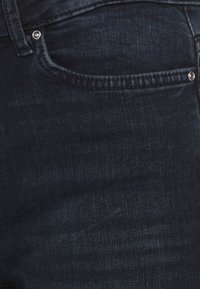 Temno modri jeans iz denima z gladko teksturo, klasičnim pet-žepnim dizajnom in enim kovinskim gumbom na sprednji strani.