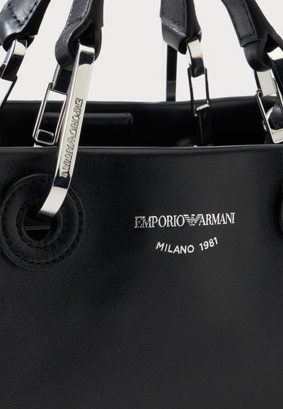 Μαύρη δερμάτινη τσάντα χειρός με ασημένιες μεταλλικές λαβές και ανάγλυφο το λογότυπο Emporio Armani Milano 1981 στο μπροστινό μέρος.