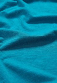 Türkiser Stoff mit einer glatten, leicht strukturierten Oberfläche, die sanfte Falten und sanfte Drapierungen zeigt. Einheitliche Farbgebung ohne Muster.