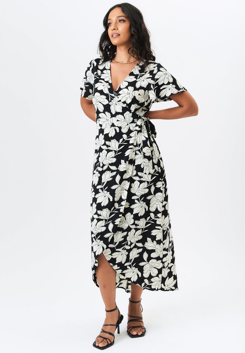 Black wrap dress featuring a white floral pattern, short sleeves, a V-neckline, and a side tie, with a slit on one side and soft fabric texture.