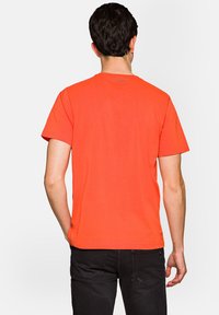 Koszulka z krótkim rękawem w jaskrawym pomarańczowym kolorze, z prostym wzornictwem, okrągłym dekoltem i bez widocznych wzorów czy ozdób.