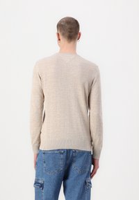 Vaaleanbeige neulepaita, jossa on pyöreä pääntie, pitkät hihat ja ribbireunat. Sileä pinta, ei näkyviä kuvioita tai koristeita.