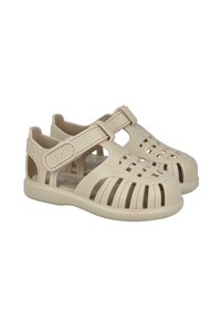 Sandalias de plástico beige con un diseño abierto, que presentan tiras y detalles recortados para la ventilación, y una punta redonda.