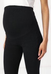 Zwarte zwangerschapsleggings met een rekbare, hoge tailleband. Zachte, gladde stof die is ontworpen om groeiende buiken comfortabel te huisvesten. Geen patronen of hardware.