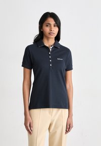 Μπλε πόλο μπλούζα με γιακά και κουμπιά. Διαθέτει αντίθετο σχέδιο στη εσωτερική πλευρά του γιακά και λογότυπο Barbour στο αριστερό στήθος.