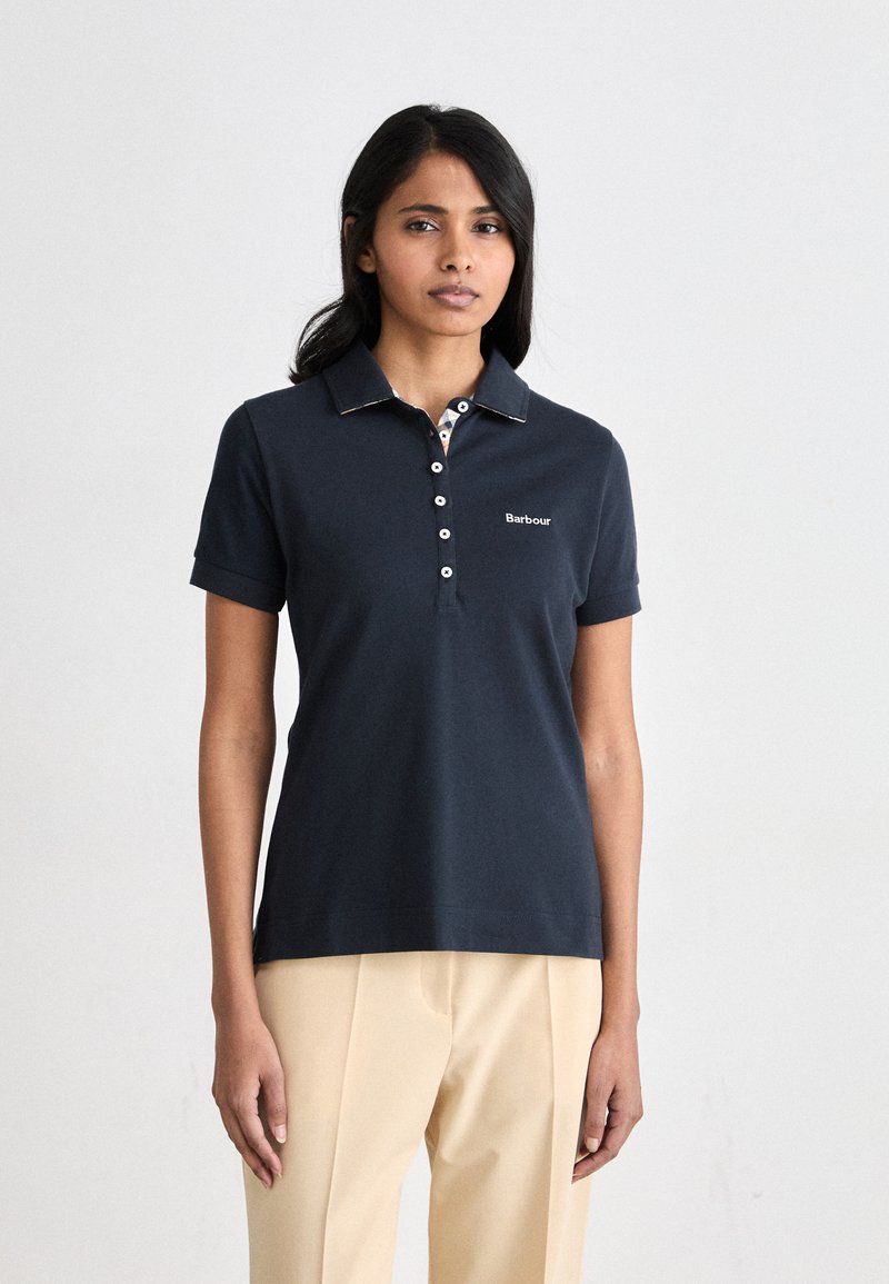 Μπλε πόλο μπλούζα με γιακά και κουμπιά. Διαθέτει αντίθετο σχέδιο στη εσωτερική πλευρά του γιακά �και λογότυπο Barbour στο αριστερό στήθος.
