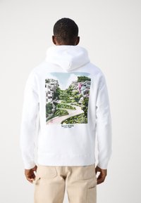Felpa bianca con cappuccio caratterizzata da una grande grafica paesaggistica vivace sul retro, che presenta sentieri, vegetazione e edifici. Polsini e orlo a coste.
