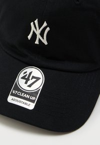 Casquette de baseball noire ajustable avec un logo "NY" brodé en blanc et un autocollant "'47 Clean Up" sur la visière.