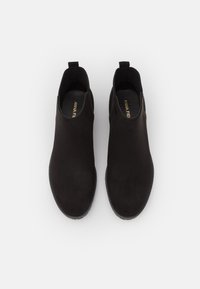 Stivaletti neri in suede con una texture liscia, pannelli laterali elastici e un linguetta, caratterizzati da una suola piatta e dettagli di cucitura sottili.