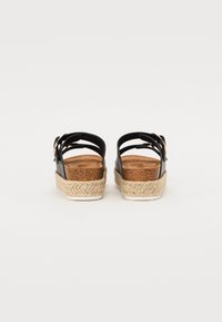 Schwarze Leder-Plateausandalen mit geflochtenen Jutesohlen, ausgestattet mit verstellbaren Riemen und einem Korkfußbett für zusätzlichen Komfort.