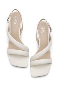 White heeled sandals featuring a strappy design, square toe, smooth leather texture, and an ankle strap with a metal buckle.