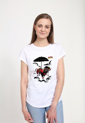 Femme portant un t-shirt blanc avec un chien cartoon en costume de super-héros rouge tenant un parapluie noir, entourée de nuages et du texte "Deadpool".
