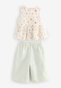 Haut crème sans manches avec imprimé floral coloré et boutons, associé à un pantalon bleu clair et blanc à rayures verticales avec taille élastique.