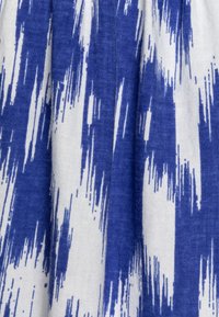 Tessuto di cotone con un motivo astratto blu e bianco caratterizzato da striature. La texture appare tessuta con una finitura morbida e leggermente ruvida.