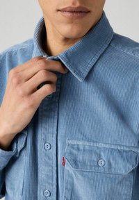 Camicia in velluto a coste blu chiaro con colletto ripiegato, chiusura con bottoni e tasca sul petto sinistro con un piccolo etichetta Levi's.
