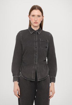 Black denim shirt with a button-up front, pointed collar, long sleeves, single chest pocket, and contrasting stitching details.