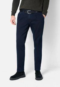 Marineblaue Baumwollchinos mit geradem Schnitt, ausgestattet mit einem Gürtel, Fronttaschen und dezenten Nähten, kombiniert mit schwarzen Wildlederstiefeln.
