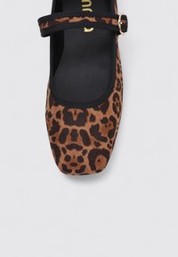 Ballerines en imprimé léopard marron et noir avec un bout rond, une sangle élastique noire et une texture de tissu lisse.