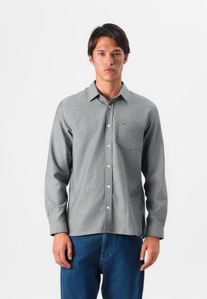 Gray long-sleeve button-up shirt with a collar, textured fabric, and a chest pocket. Features a small green logo on the left side.