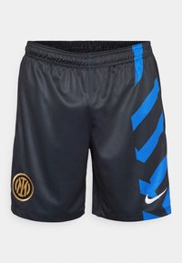 Shorts de sport noirs avec une finition texturée, présentant des rayures diagonales bleues sur les côtés et un logo circulaire doré. Marque Nike en blanc.