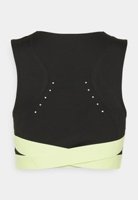 Crop top de sport noir avec une large bande jaune à l'ourlet, agrémenté de clous argentés décoratifs et d'une coupe élégante et ajustée.