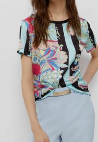 Blusa a maniche corte con motivo floreale e righe in colori pastello, realizzata in un tessuto morbido, con scollo e maniche nere.